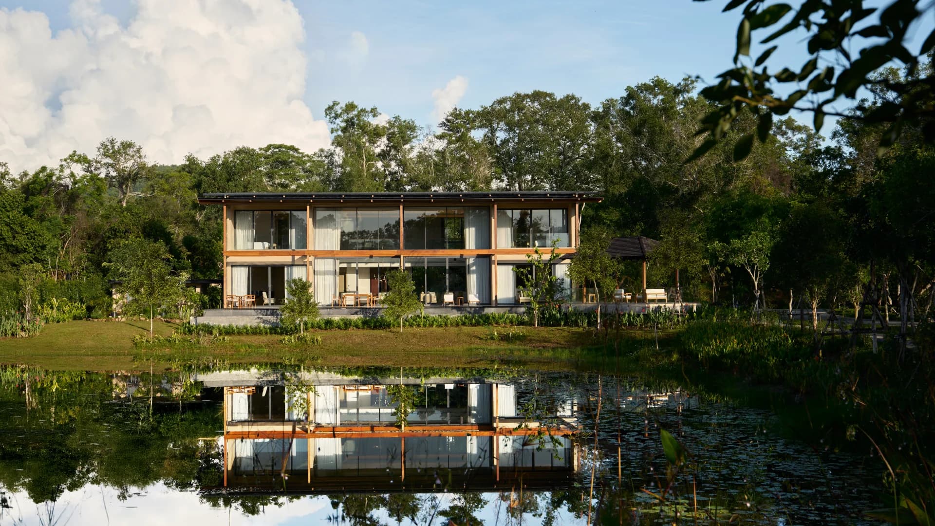 Una villa VANA 4 construida frente a un lago sereno en Tri Vananda
